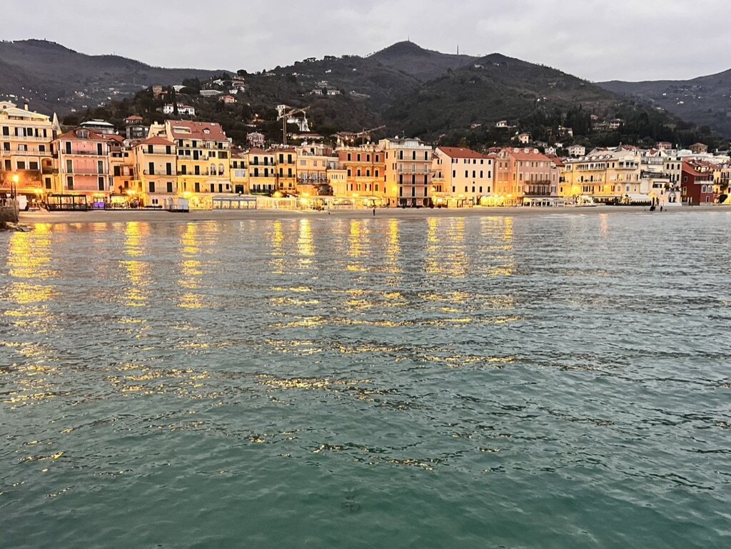 Illuminated waterfront town and mountains scouted in Italy